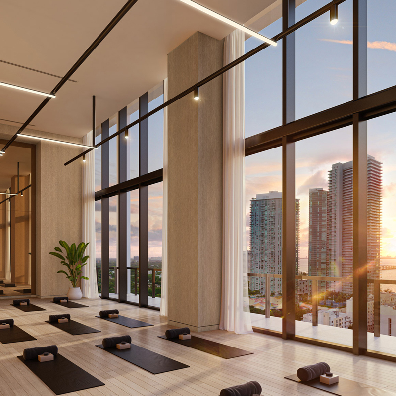 The yoga studio at Forma Miami. Room with hardwood floors, double-height ceilings, natural light, and Miami skyline views.